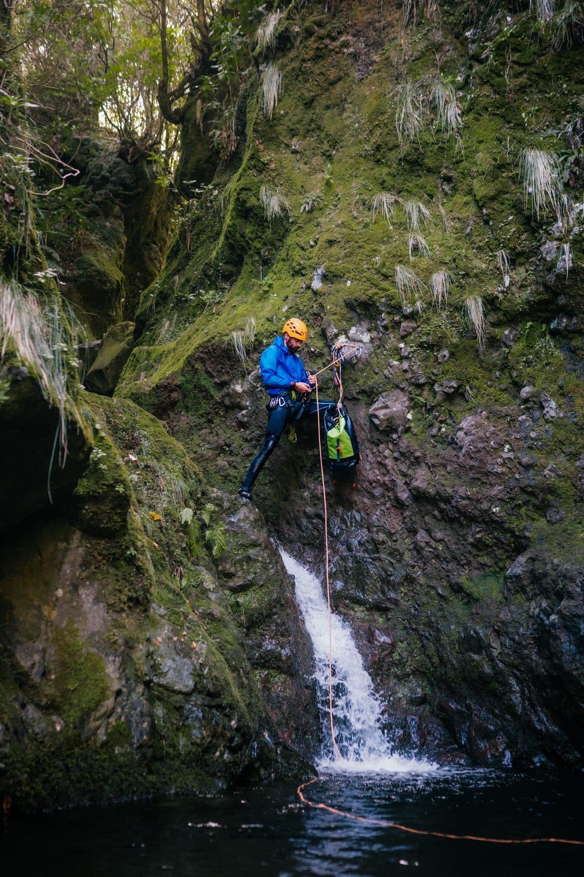 Un guía montando la cuerda sobre una cascada antes de que el grupo haga rápel