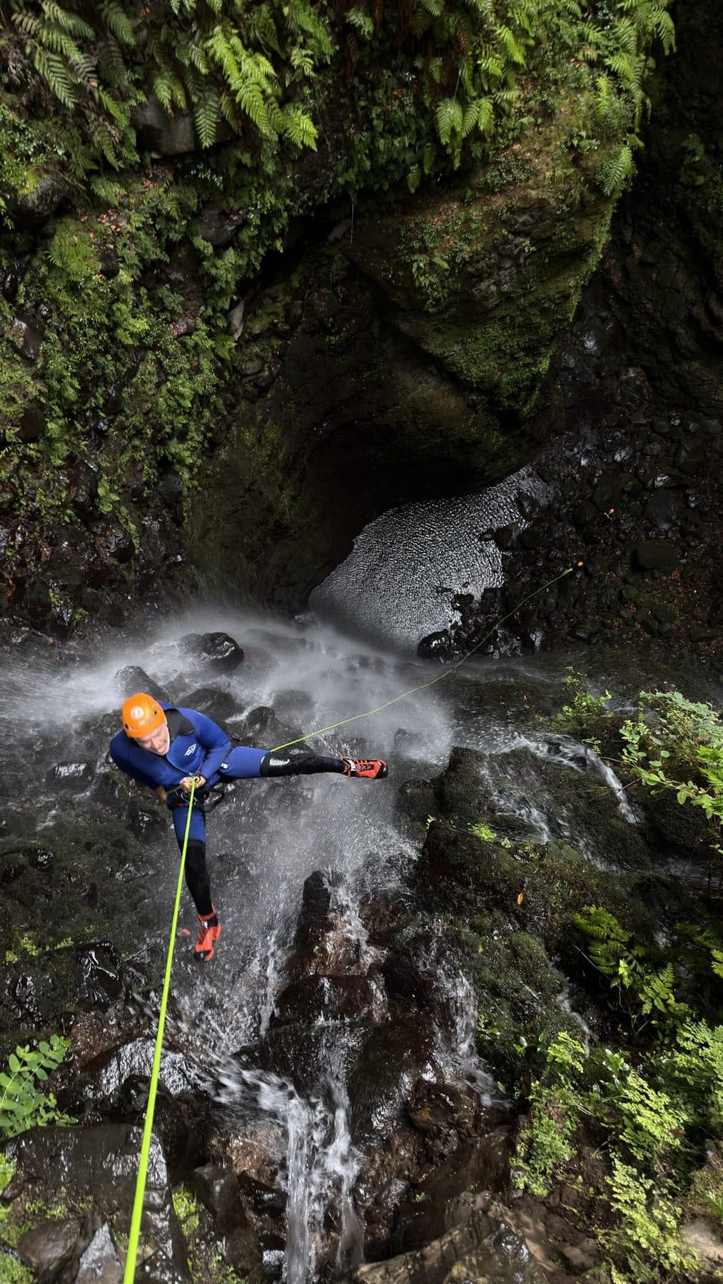 Vista desde arriba de un barranquista haciendo rápel a través de una cascada
